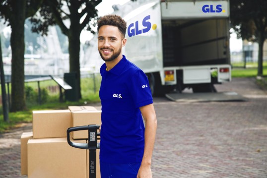 GLS Zustellfahrer verlässt mit Paketen ein Geschäft um sie zu versenden