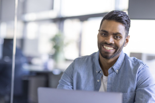 Un employé GLS souriant devant son pc