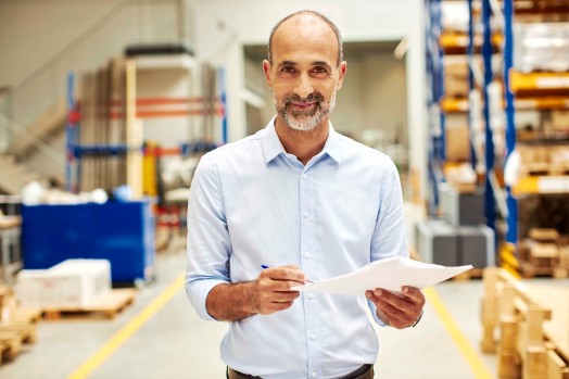 middle aged man holding a document in warehouse