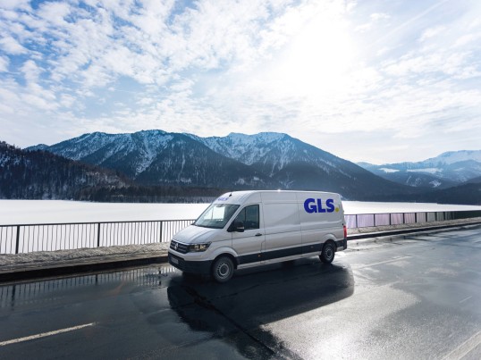 GLS delivery van drives between a forest and a field