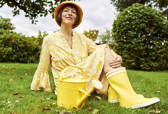 Frau mit Gießkanne sitzt auf dem Rasen
