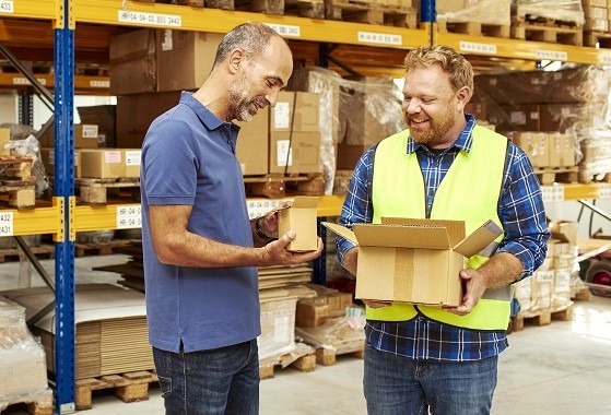 Two men in a warehouse holding small boxes
