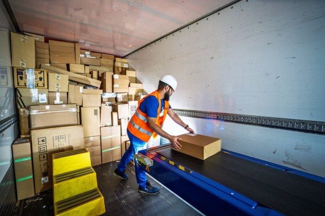 Worker placing a parcel on a conveyor belt