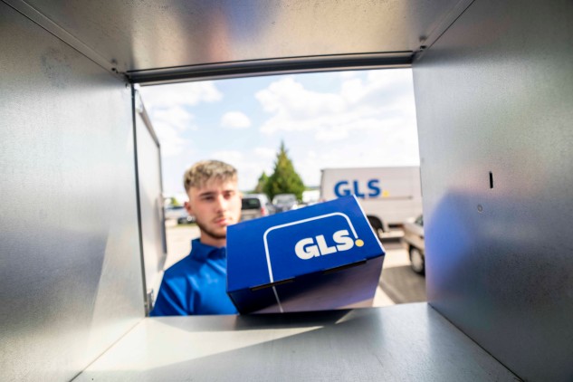 Parcel delivery into a locker from inside view: GLS courier placing a blue package into a locker in a last-mile delivery setting.