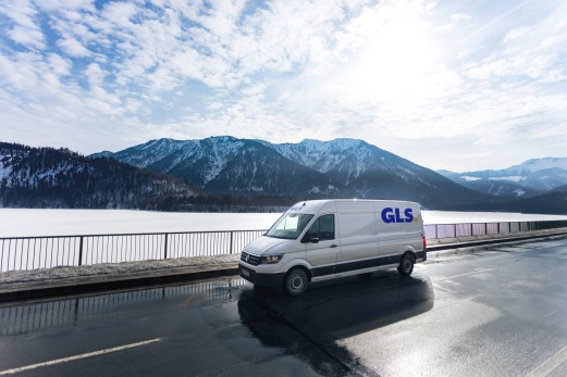 GLS kuorma-auto ajaa avoimella tiellä, takana on vuorimaisema.