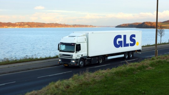 GLS long truck driving between a field and a forest