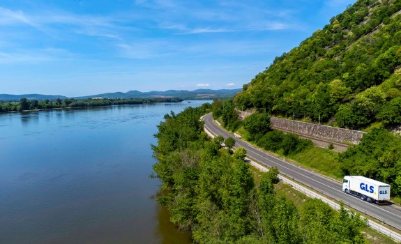 A GLS truck driving alongside a river