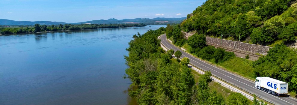 A GLS truck driving alongside a river