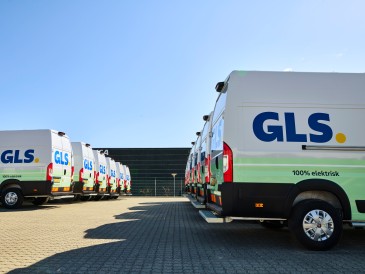 Fleet of GLS electric vans parked, showcasing the company’s commitment to achieving net-zero emissions by 2045.