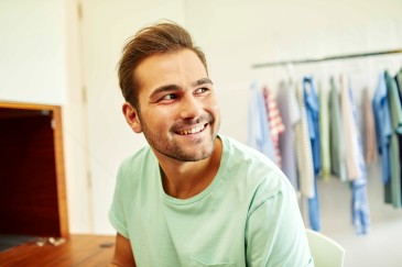 young-man-smiling-in-front-of-clothes-rack