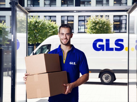 GLS driver with a parcel on his hand happy to work as a courier