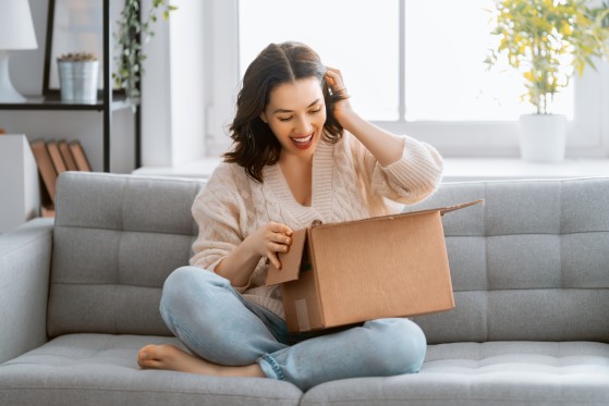 Woman sitting on couch with parcel in hands