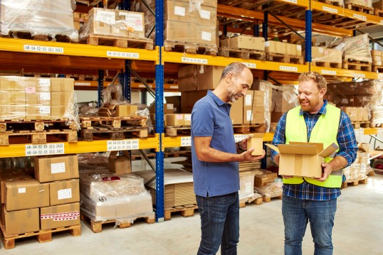GLS delivery driver delivers parcels to warehouse worker